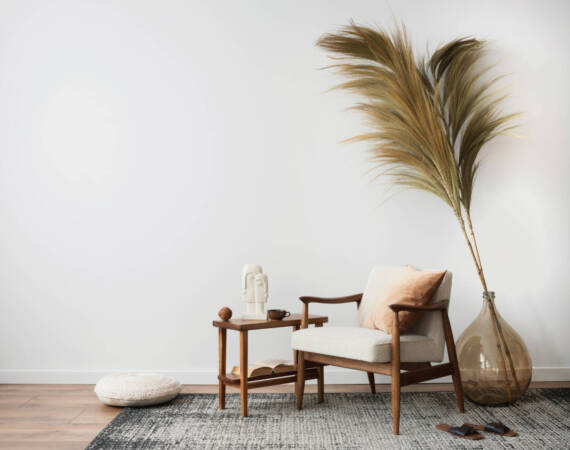 Interior design of aesthetic and minimalist living room with boucle armchair, wooden coffee table, pedant lamp, beautiful leafs in vase, decoration and personal accessories. Copy space. Home decor.